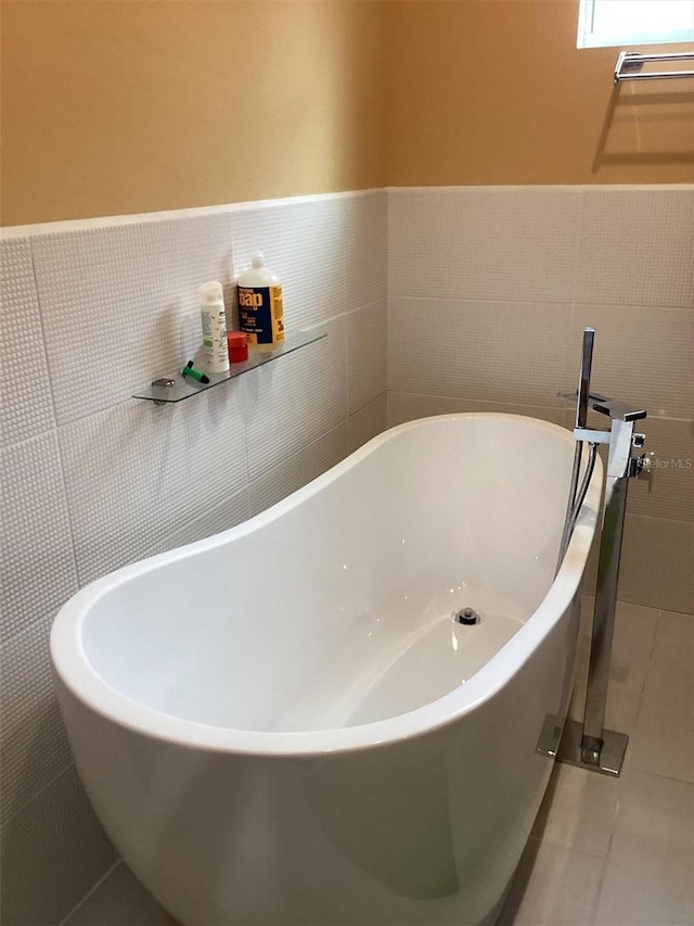 bathroom with tile patterned floors, a washtub, and tile walls