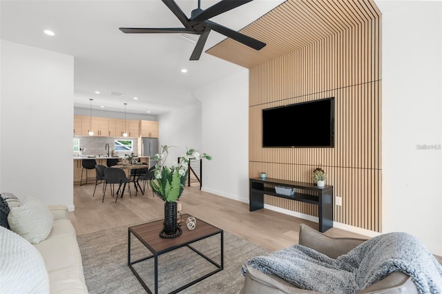 living room with ceiling fan, sink, and light wood-type flooring