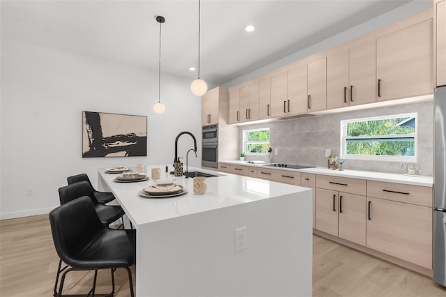 kitchen featuring light brown cabinetry, a center island with sink, and light hardwood / wood-style flooring