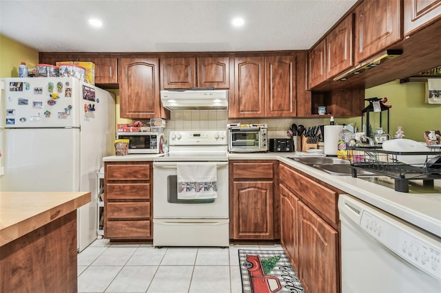 kitchen featuring decorative backsplash, light tile patterned floors, white appliances, and sink