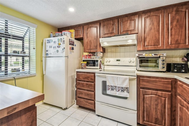 kitchen with a textured ceiling, white appliances, backsplash, and light tile patterned floors