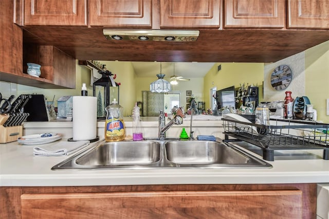 kitchen with lofted ceiling, ceiling fan, sink, and decorative light fixtures