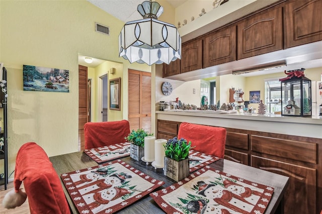 dining room featuring wood-type flooring and vaulted ceiling