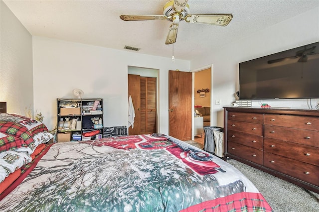 carpeted bedroom with ceiling fan, a textured ceiling, and a closet