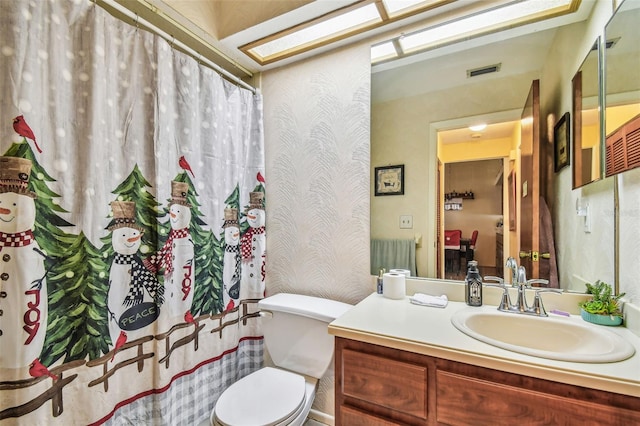 bathroom with vanity, toilet, and a skylight