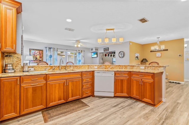 kitchen featuring sink, decorative light fixtures, light hardwood / wood-style floors, white dishwasher, and kitchen peninsula