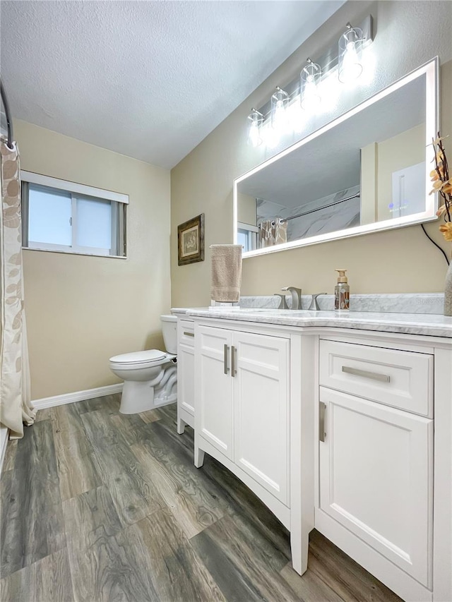 bathroom featuring a textured ceiling, vanity, hardwood / wood-style flooring, and toilet