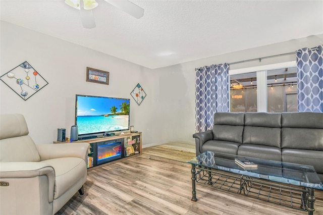 living room with a textured ceiling, hardwood / wood-style flooring, and ceiling fan