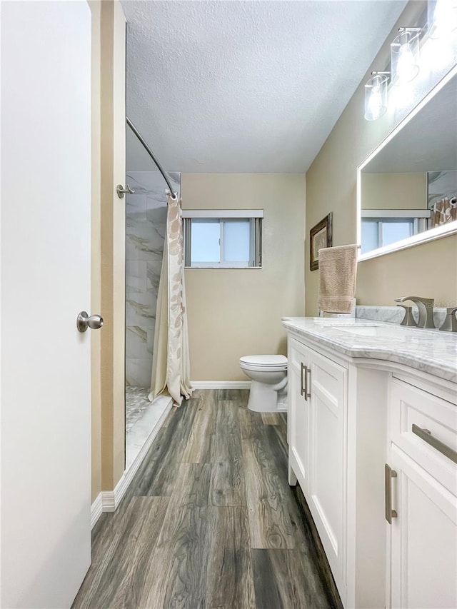 bathroom featuring hardwood / wood-style flooring, toilet, a textured ceiling, a shower with shower curtain, and vanity