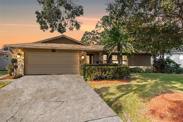 ranch-style house featuring a garage and a yard