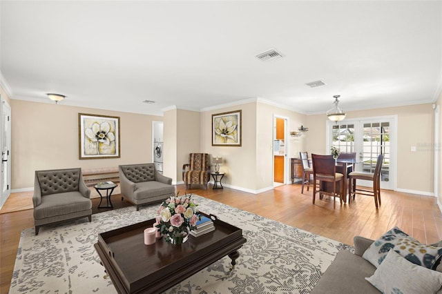 living room with light hardwood / wood-style flooring, french doors, and ornamental molding