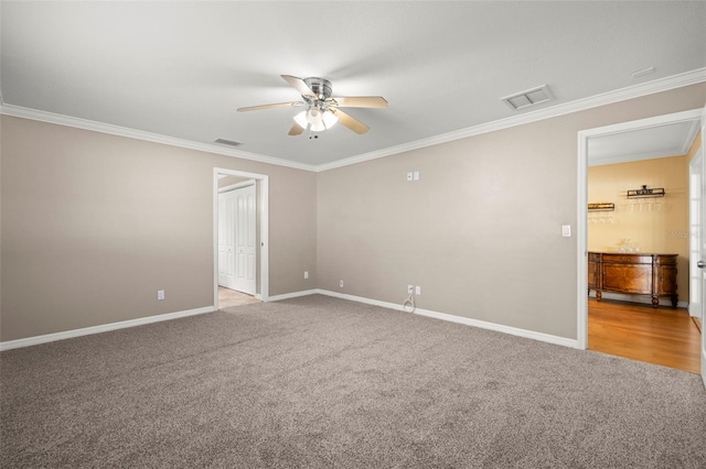 spare room with ceiling fan, crown molding, and light carpet