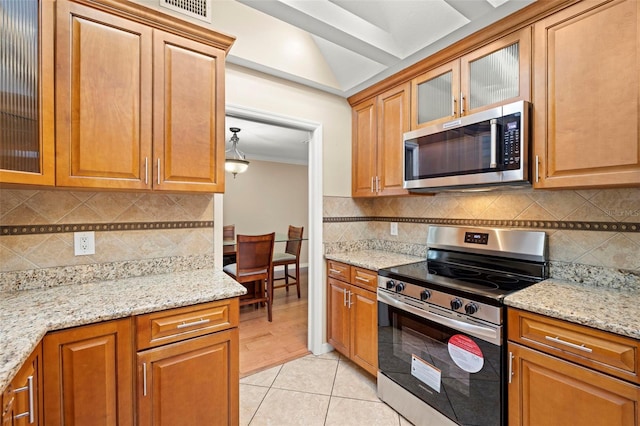 kitchen featuring backsplash, light stone countertops, light tile patterned flooring, and appliances with stainless steel finishes