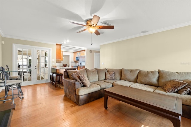 living room with french doors, light hardwood / wood-style floors, ceiling fan, and crown molding