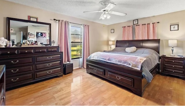 bedroom featuring ceiling fan, light wood-type flooring, and a textured ceiling