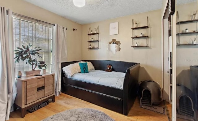 bedroom featuring light hardwood / wood-style floors and a textured ceiling