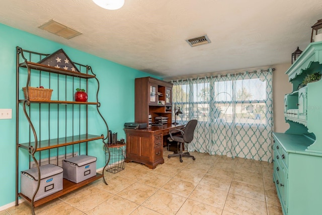 home office with a textured ceiling and light tile patterned flooring