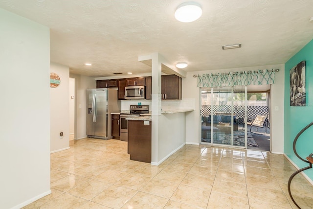 kitchen featuring light tile patterned floors, a textured ceiling, dark brown cabinets, light stone counters, and stainless steel appliances