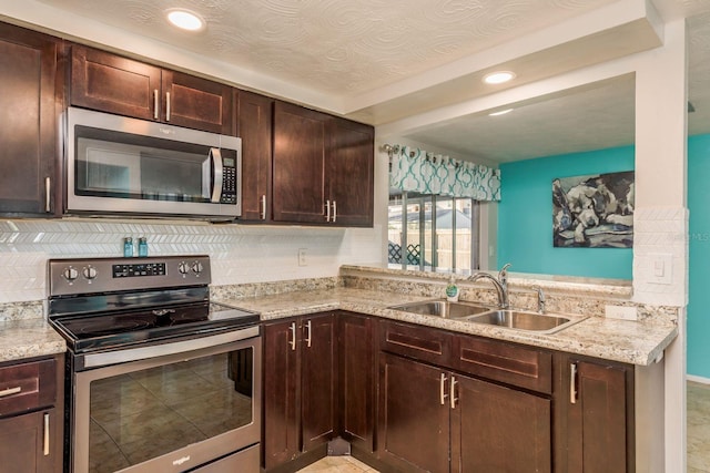 kitchen featuring light stone countertops, appliances with stainless steel finishes, tasteful backsplash, dark brown cabinetry, and sink