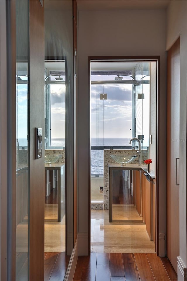 hall with dark hardwood / wood-style flooring, a water view, and sink