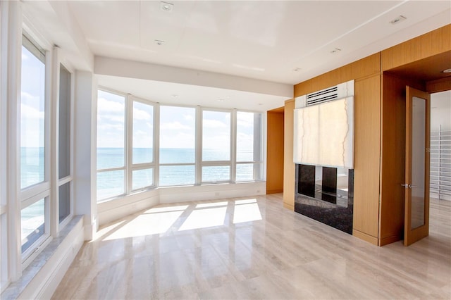 unfurnished living room with wood walls, light hardwood / wood-style flooring, and a water view