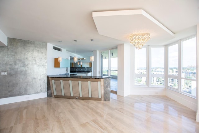 kitchen with kitchen peninsula, decorative light fixtures, a chandelier, and dark stone counters