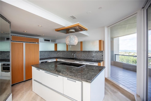 kitchen with pendant lighting, oven, decorative backsplash, paneled built in refrigerator, and white cabinetry