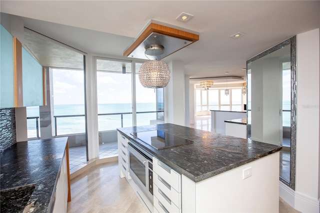 kitchen with a chandelier, decorative light fixtures, a water view, black electric cooktop, and white cabinets