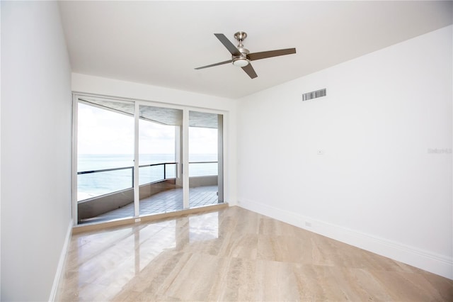 unfurnished room featuring light wood-type flooring, a water view, and ceiling fan