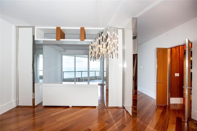 empty room featuring wood-type flooring and an inviting chandelier