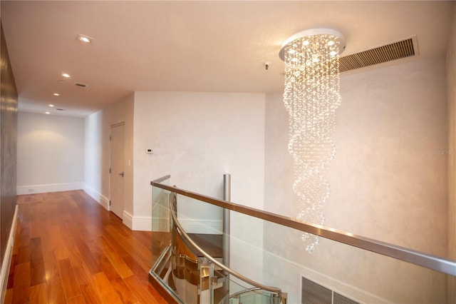 corridor featuring wood-type flooring and an inviting chandelier