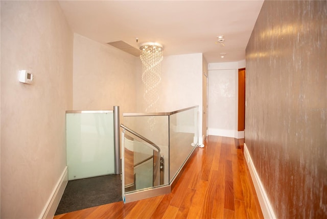 hall with hardwood / wood-style floors and an inviting chandelier