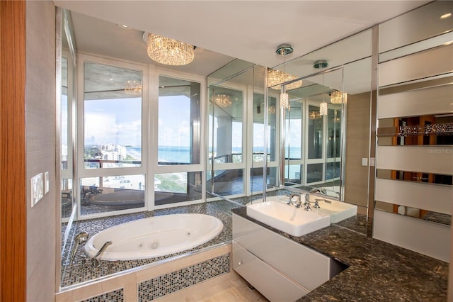 bathroom with vanity, a notable chandelier, and tiled tub