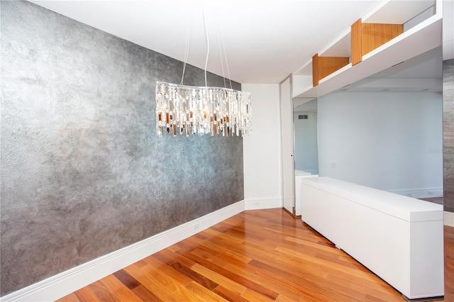 unfurnished dining area with a chandelier and light hardwood / wood-style floors