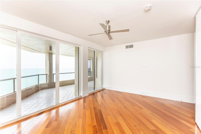 unfurnished room with hardwood / wood-style floors, ceiling fan, and a water view