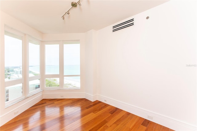 empty room with hardwood / wood-style flooring and track lighting