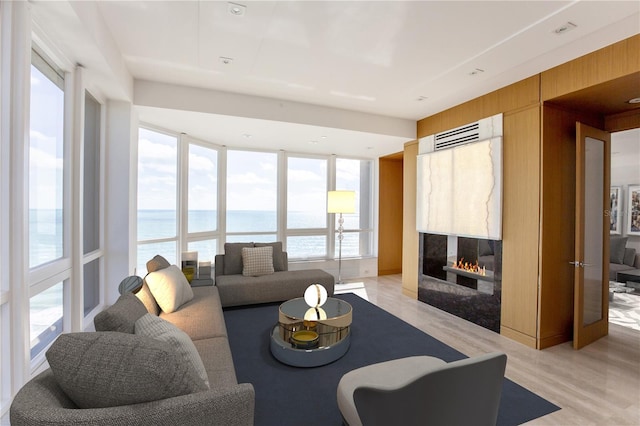 living room with a high end fireplace, a water view, and light wood-type flooring