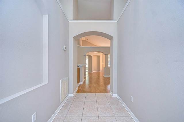 hall featuring light tile patterned floors and a high ceiling