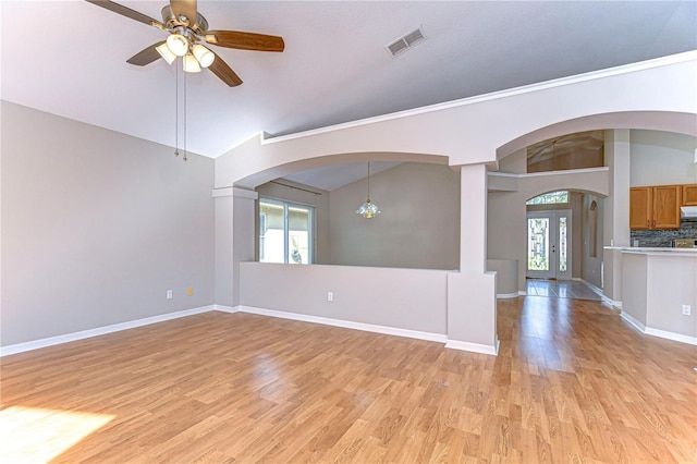 empty room featuring ceiling fan with notable chandelier, light hardwood / wood-style floors, vaulted ceiling, and french doors