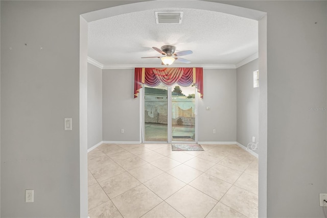 tiled empty room with ceiling fan, a textured ceiling, and ornamental molding