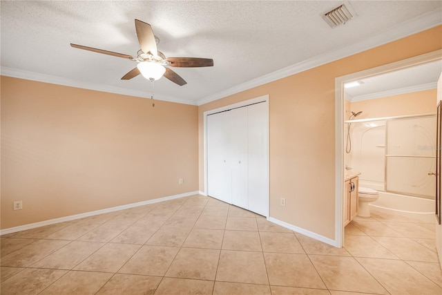 unfurnished bedroom featuring a textured ceiling, ensuite bath, ceiling fan, and ornamental molding