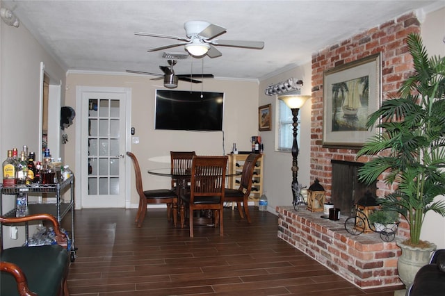 dining area featuring ceiling fan, dark hardwood / wood-style flooring, ornamental molding, and a brick fireplace