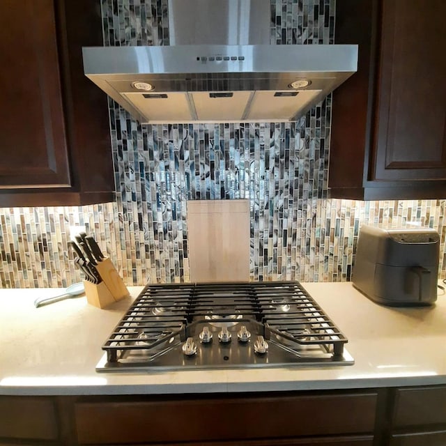 kitchen featuring tasteful backsplash, dark brown cabinets, exhaust hood, and stainless steel gas cooktop