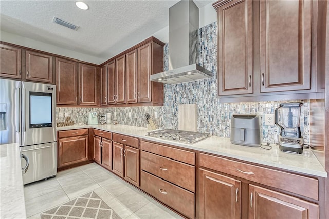 kitchen with wall chimney exhaust hood, decorative backsplash, a textured ceiling, appliances with stainless steel finishes, and light tile patterned flooring