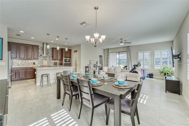 dining room featuring a textured ceiling, sink, light tile patterned flooring, and ceiling fan with notable chandelier