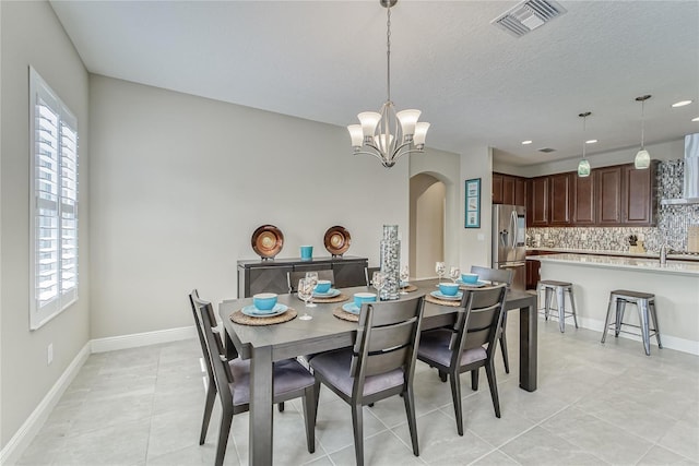 tiled dining area with sink, a textured ceiling, and an inviting chandelier