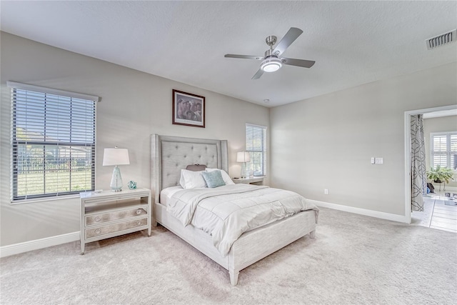 bedroom with ceiling fan, carpet floors, and a textured ceiling