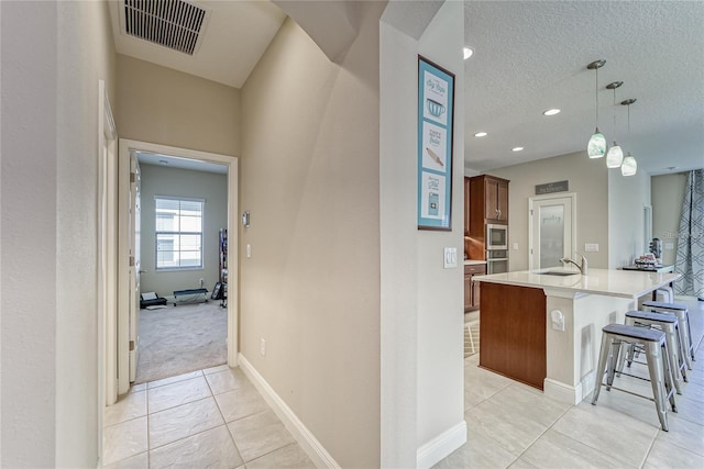 hallway with light tile patterned floors, a textured ceiling, and sink