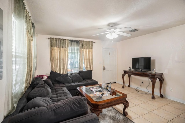 living room featuring ceiling fan, light tile patterned flooring, and a textured ceiling