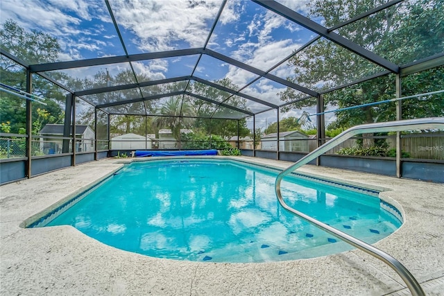 view of swimming pool featuring glass enclosure, a patio, and a storage shed